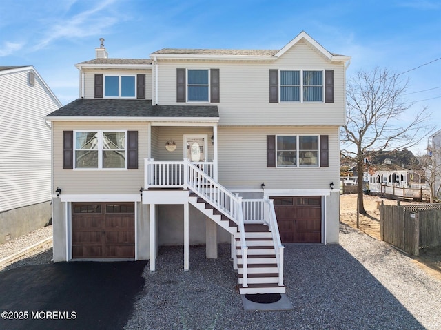 view of front of property featuring a garage, stairway, and gravel driveway