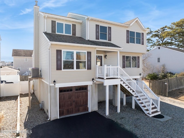 view of front of property featuring driveway, a chimney, an attached garage, stairs, and fence