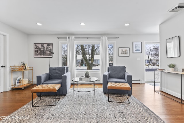 living area with recessed lighting, visible vents, and wood finished floors