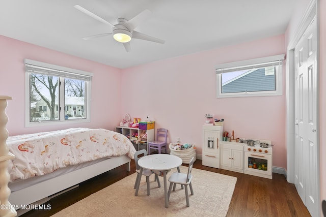 bedroom featuring ceiling fan, baseboards, dark wood finished floors, and a closet