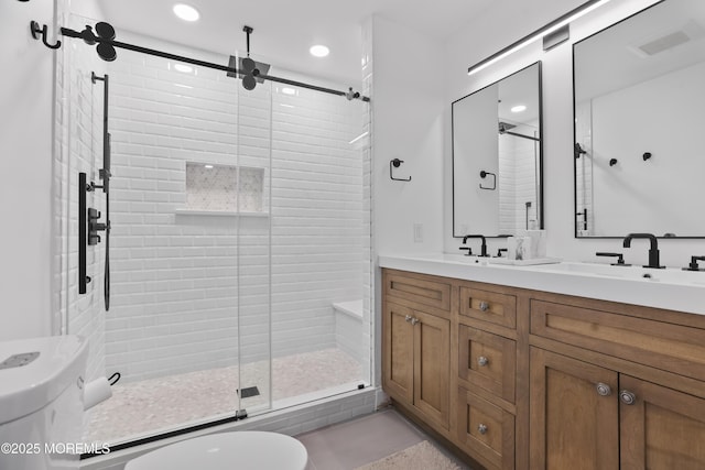 full bath with a sink, a shower stall, toilet, and double vanity