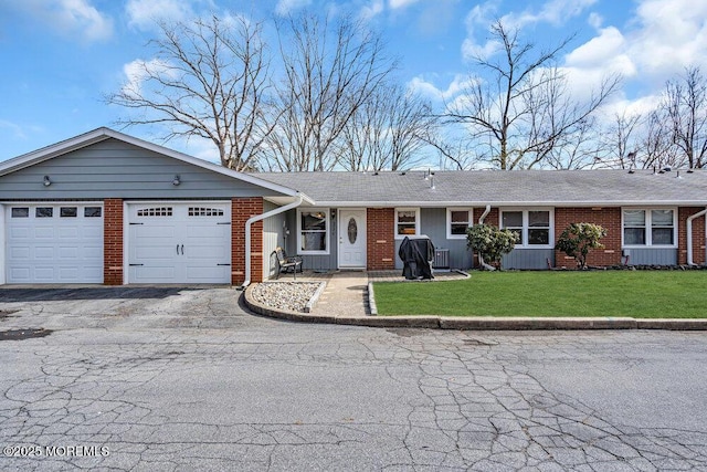 ranch-style home featuring a garage, brick siding, driveway, and a front lawn