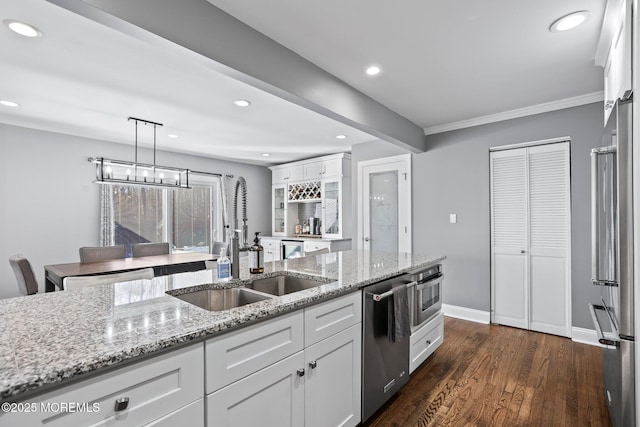 kitchen with dark wood-style floors, light stone countertops, a sink, stainless steel appliances, and white cabinets