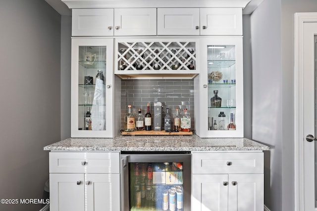 bar with beverage cooler, decorative backsplash, and a bar