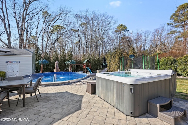 view of pool with a patio, outdoor dining area, a hot tub, an outdoor structure, and a playground