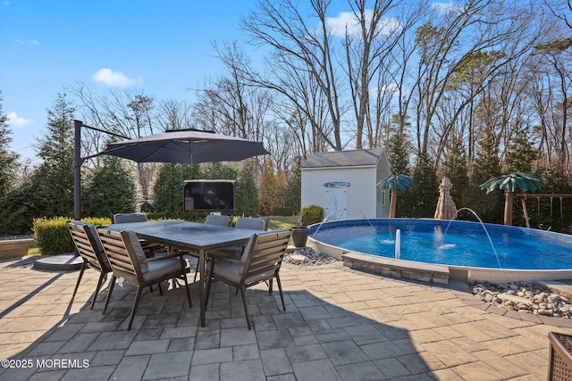 outdoor pool featuring a patio area, outdoor dining space, a storage unit, and an outdoor structure