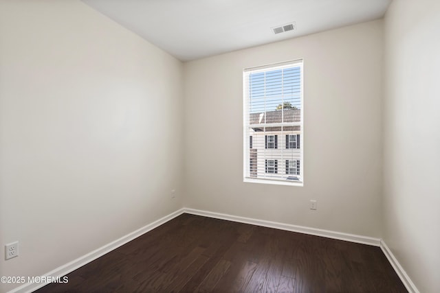 empty room featuring baseboards, visible vents, and dark wood-type flooring