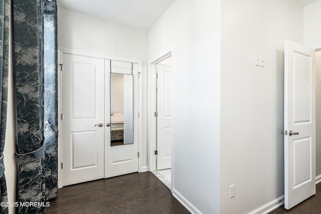 corridor with dark wood-style flooring and baseboards