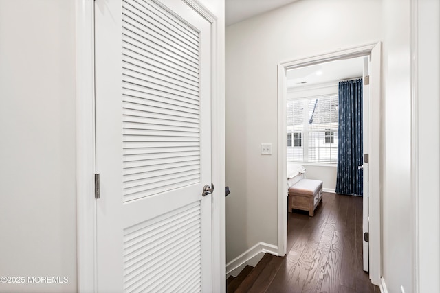 hall featuring dark wood-type flooring and baseboards