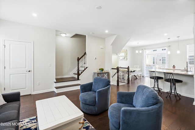 living room featuring stairs, baseboards, dark wood finished floors, and recessed lighting