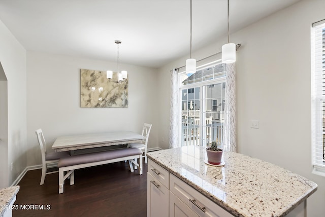 kitchen featuring hanging light fixtures, dark wood finished floors, light stone countertops, and white cabinets