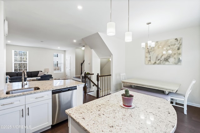 kitchen with a sink, white cabinets, open floor plan, dishwasher, and decorative light fixtures