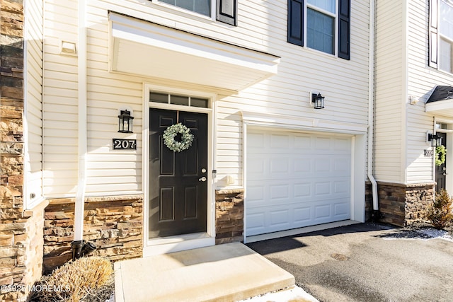 doorway to property featuring a garage and stone siding