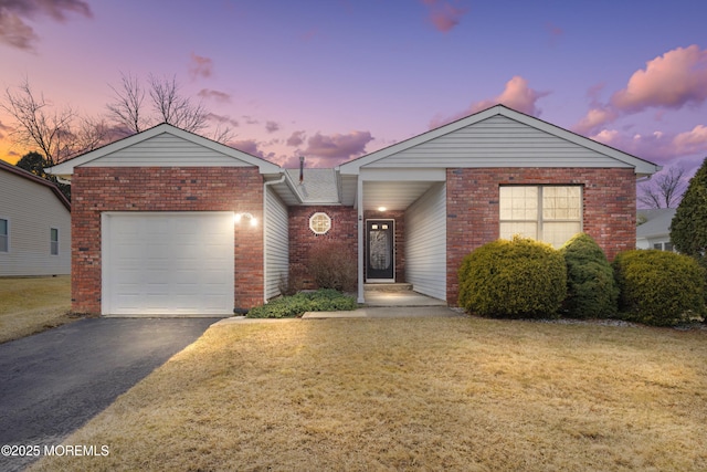 ranch-style home featuring driveway, a yard, an attached garage, and brick siding