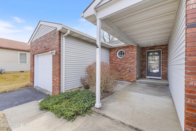 property entrance featuring a garage, brick siding, and aphalt driveway