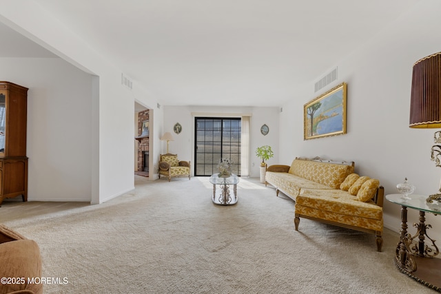 carpeted living room featuring a fireplace, visible vents, and baseboards