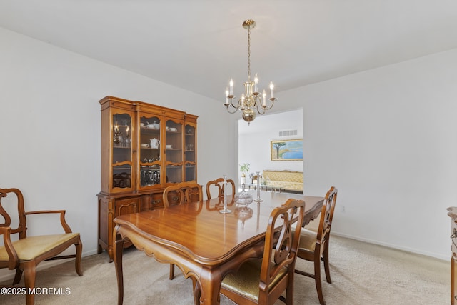 dining room featuring light carpet, baseboards, and a notable chandelier