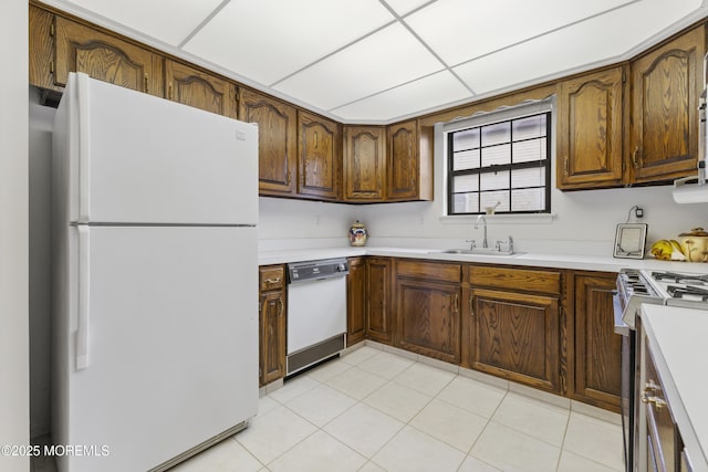 kitchen featuring white appliances, light countertops, a sink, and light tile patterned flooring