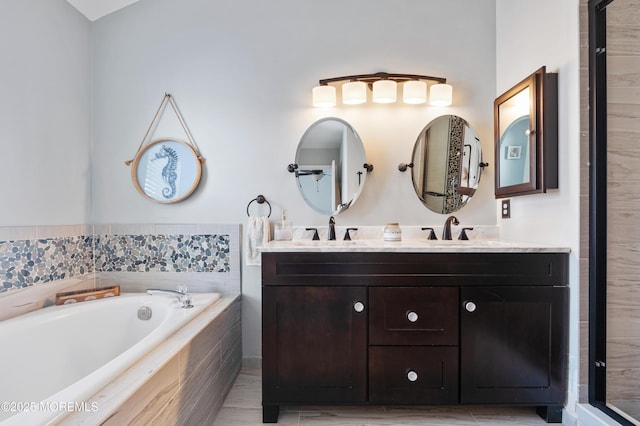 full bathroom featuring double vanity, a garden tub, and a sink