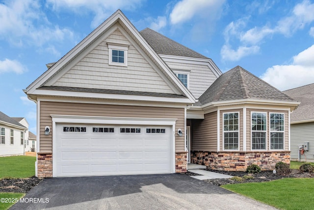 craftsman house featuring a garage, driveway, a shingled roof, and stone siding