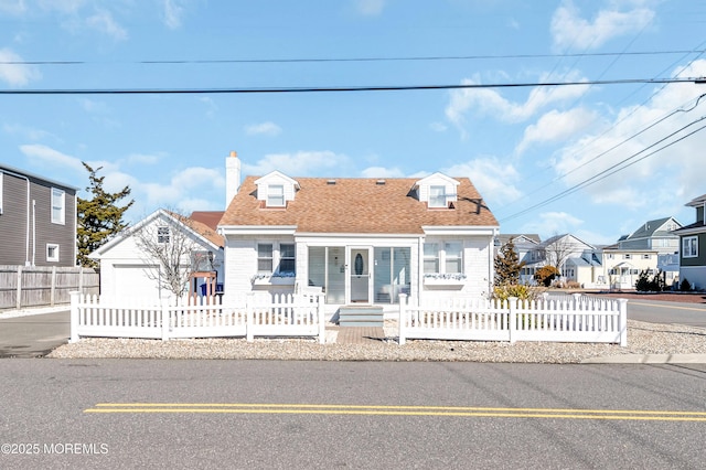 cape cod home with a shingled roof, a fenced front yard, a chimney, and an outdoor structure