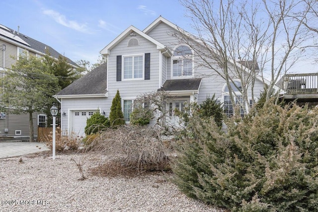 traditional-style home with roof with shingles, driveway, and an attached garage