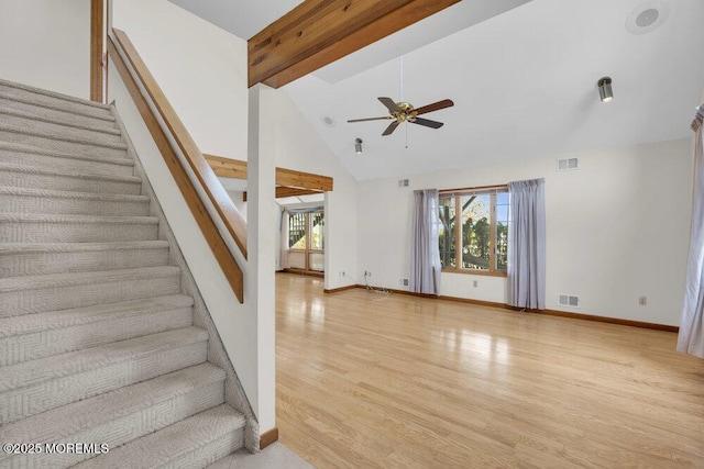 stairway with high vaulted ceiling, beam ceiling, visible vents, and wood finished floors