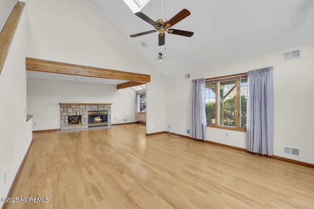 unfurnished living room with high vaulted ceiling, a stone fireplace, light wood-type flooring, and visible vents