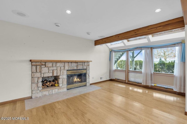 unfurnished living room with lofted ceiling with beams, a stone fireplace, recessed lighting, wood finished floors, and baseboards