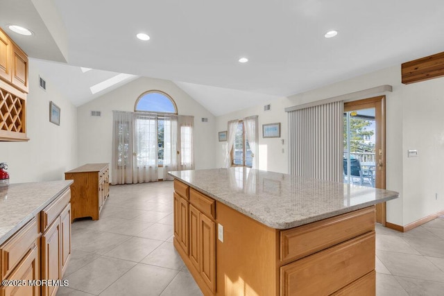 kitchen featuring vaulted ceiling with skylight, light tile patterned flooring, a kitchen island, and visible vents