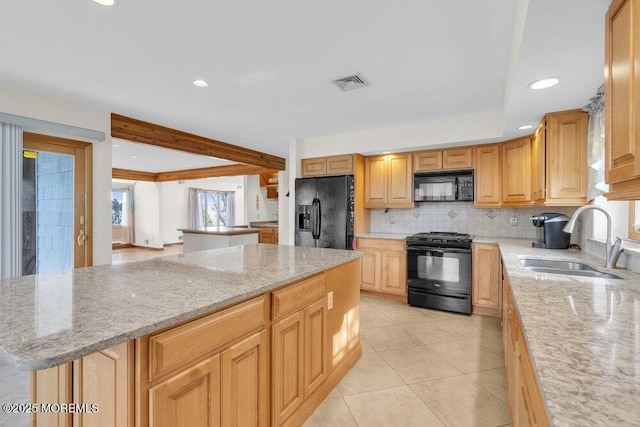 kitchen featuring a sink, visible vents, backsplash, light stone countertops, and black appliances