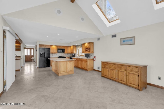 kitchen with a skylight, light countertops, visible vents, a kitchen island, and black appliances