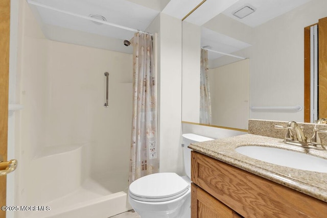 bathroom with a shower stall, toilet, and vanity