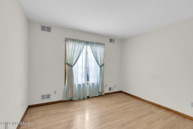 spare room featuring light wood-style floors, baseboards, and visible vents