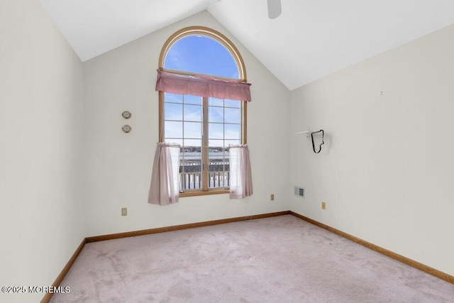 carpeted empty room featuring baseboards and vaulted ceiling