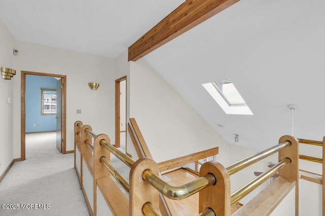 hall with lofted ceiling with skylight, baseboards, light colored carpet, and an upstairs landing