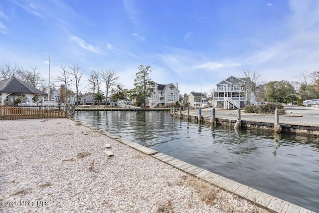 view of dock with a gazebo, a water view, and a residential view