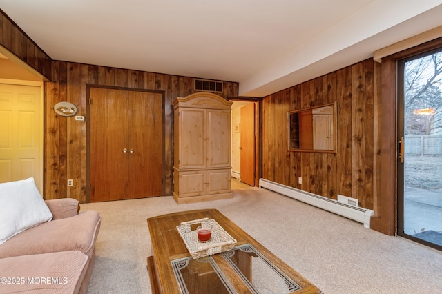 living area with light carpet, baseboard heating, and wooden walls