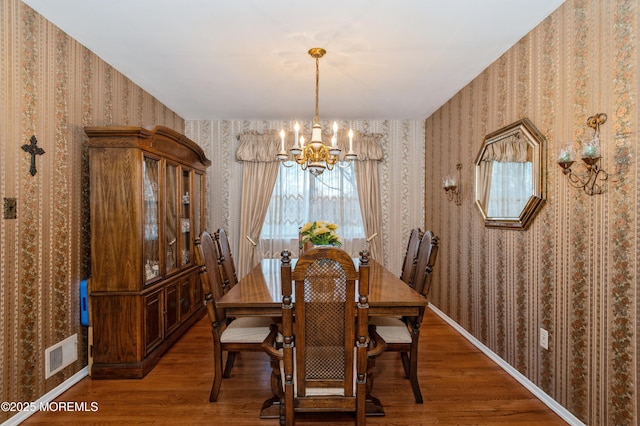 dining area featuring wallpapered walls, visible vents, wood finished floors, and an inviting chandelier