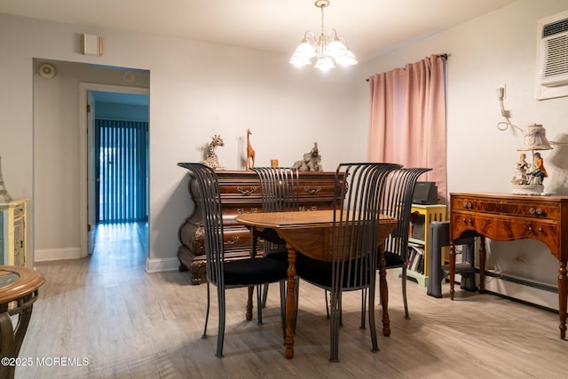 dining room featuring a chandelier, light wood-type flooring, a wall mounted air conditioner, and baseboards