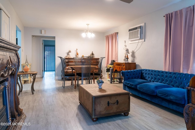 living area with light wood-style floors, a wall unit AC, a notable chandelier, and baseboards