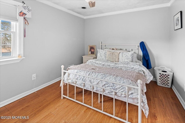 bedroom with ornamental molding, wood finished floors, and baseboards