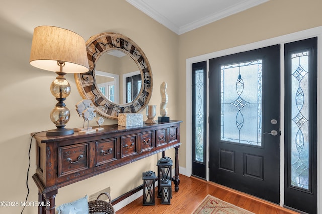 foyer featuring light wood-type flooring, crown molding, and baseboards