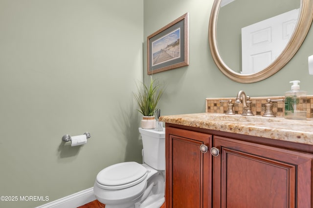 bathroom featuring toilet, baseboards, and vanity