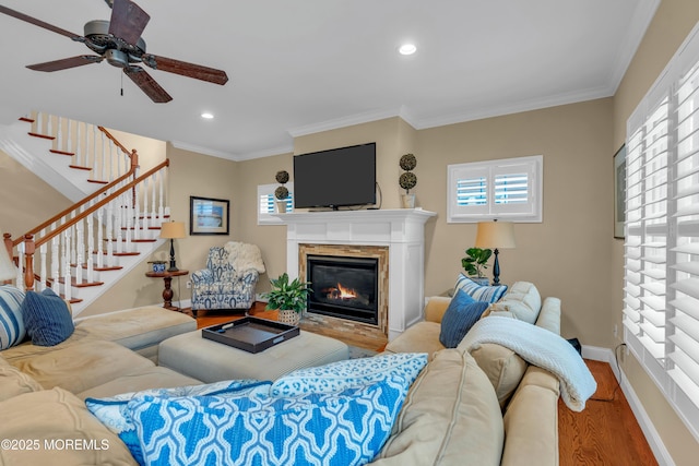 living area featuring recessed lighting, wood finished floors, baseboards, a glass covered fireplace, and crown molding