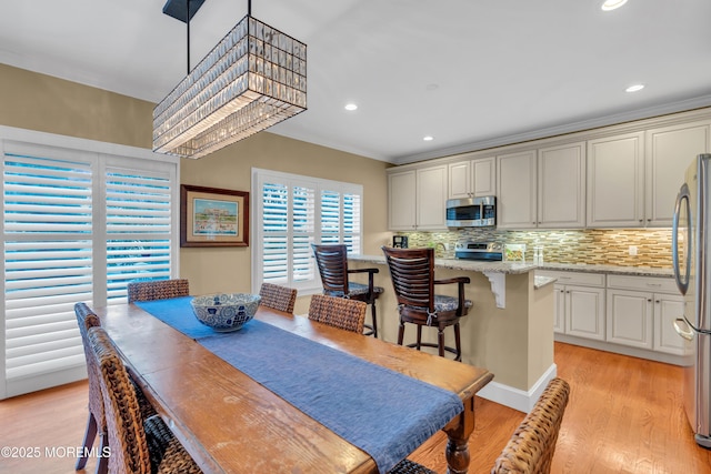 dining area featuring ornamental molding, light wood finished floors, recessed lighting, and a notable chandelier