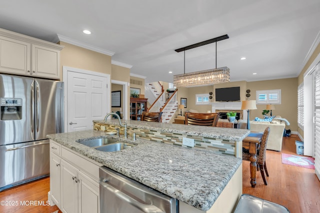 kitchen featuring stainless steel appliances, a sink, and an island with sink