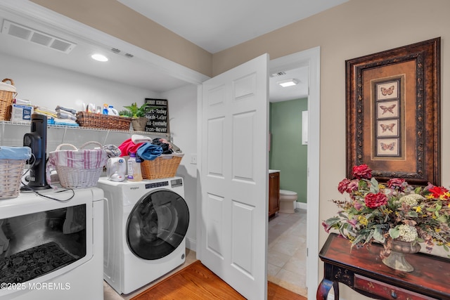 washroom featuring laundry area, visible vents, light wood-style floors, and washing machine and clothes dryer