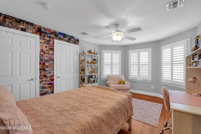 bedroom with a ceiling fan, visible vents, light wood-style flooring, and baseboards