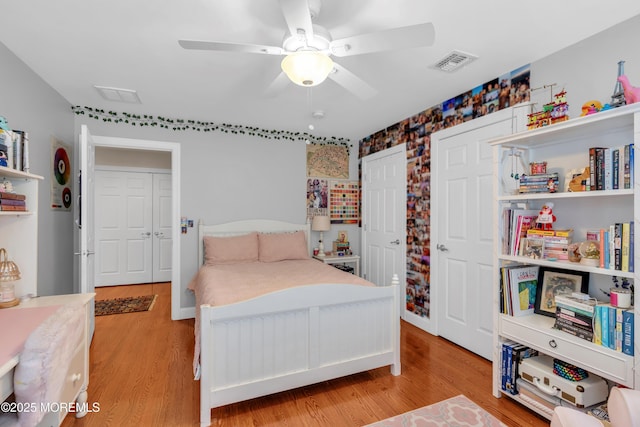 bedroom with light wood-type flooring, ceiling fan, and visible vents